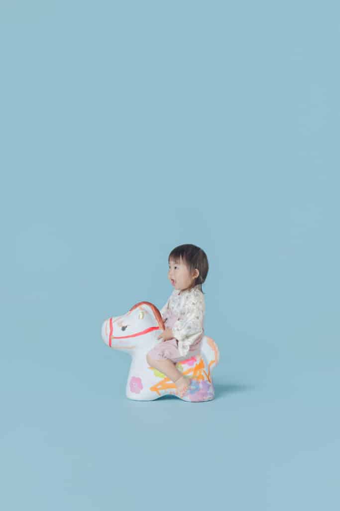 ワークショップで絵付けした馬に乗っている参加者のお子さん。